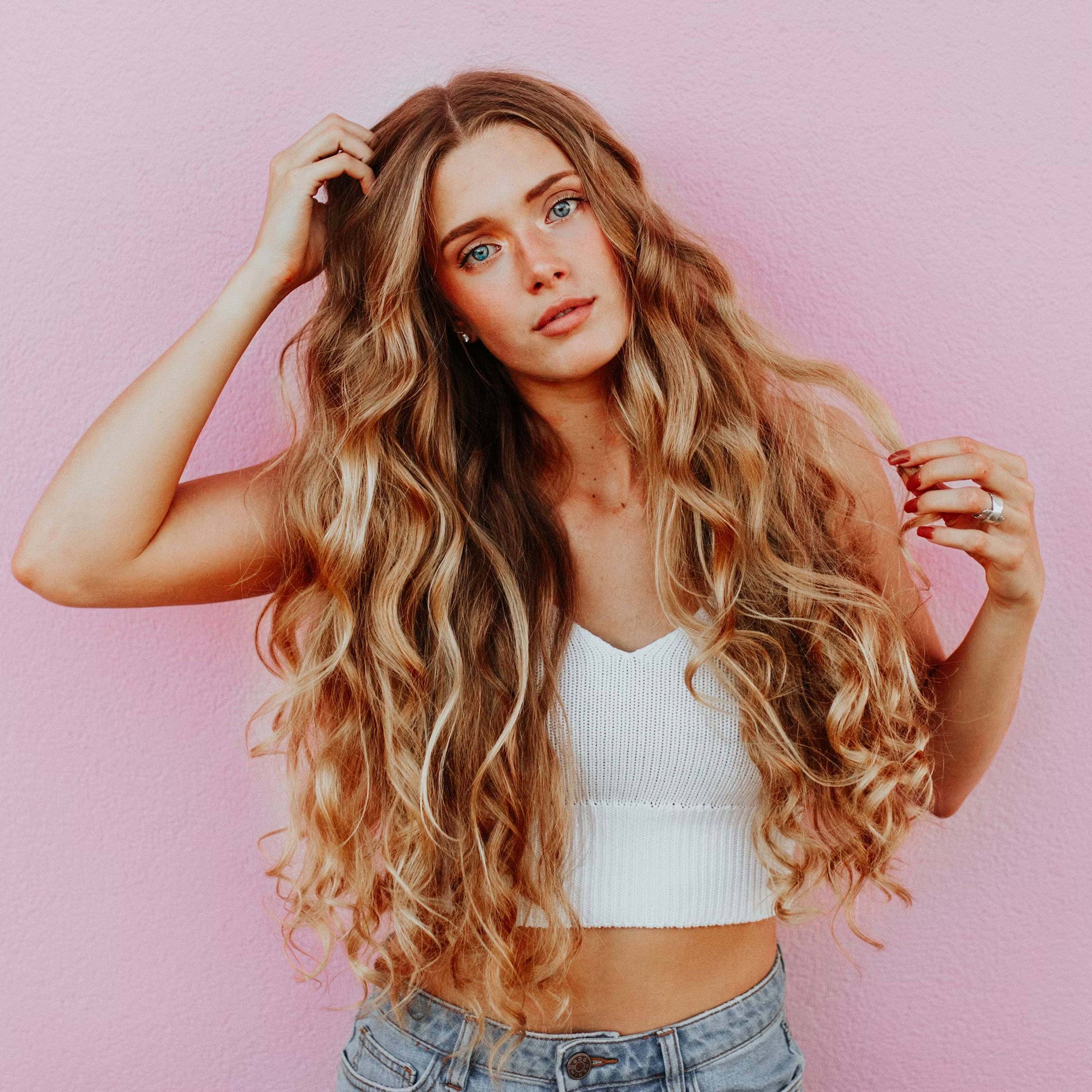 woman with long, light brown smooth hair and a pink background