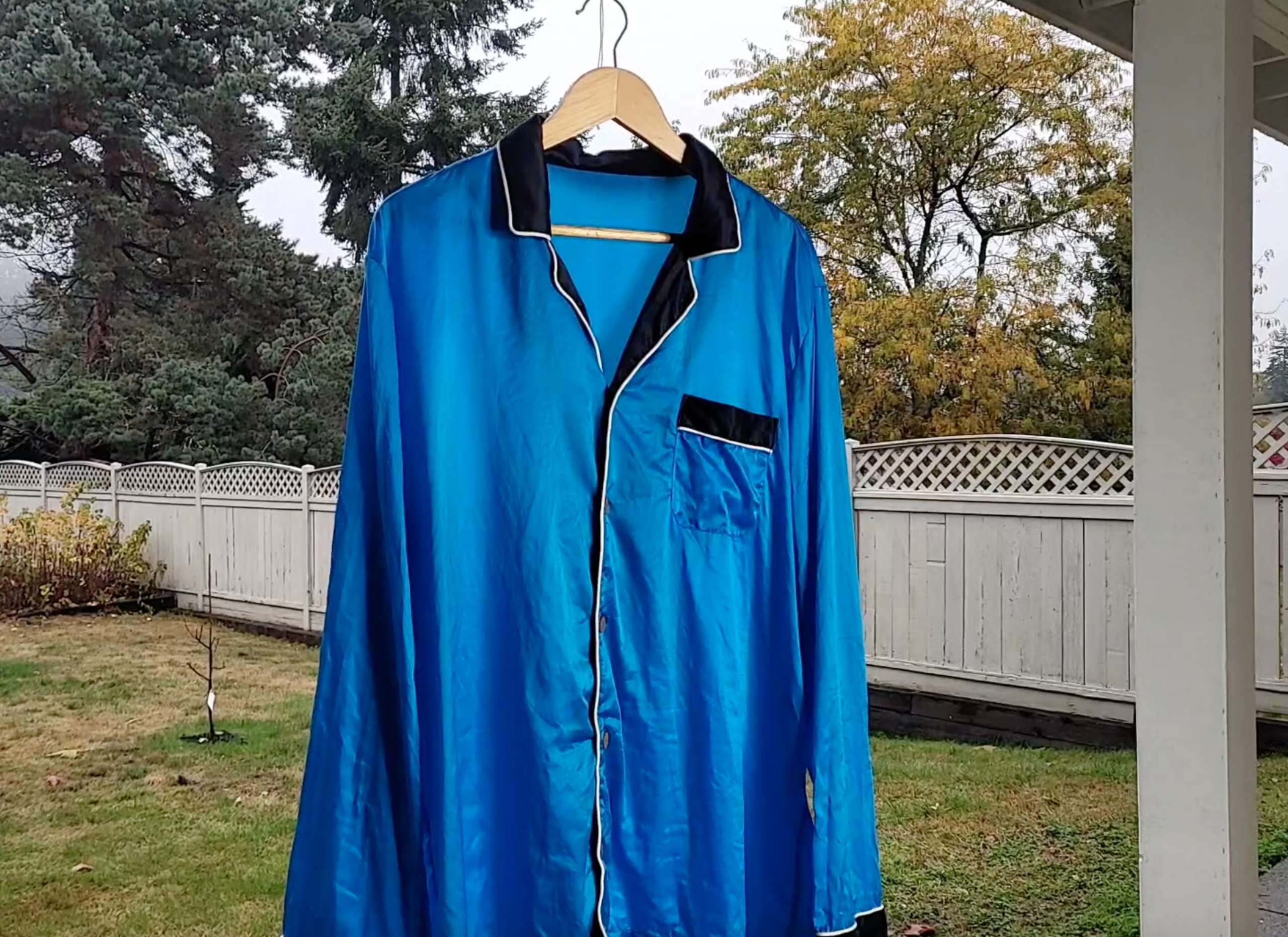 photo of a blue satin shirt hanging out to air dry outside in a shaded area