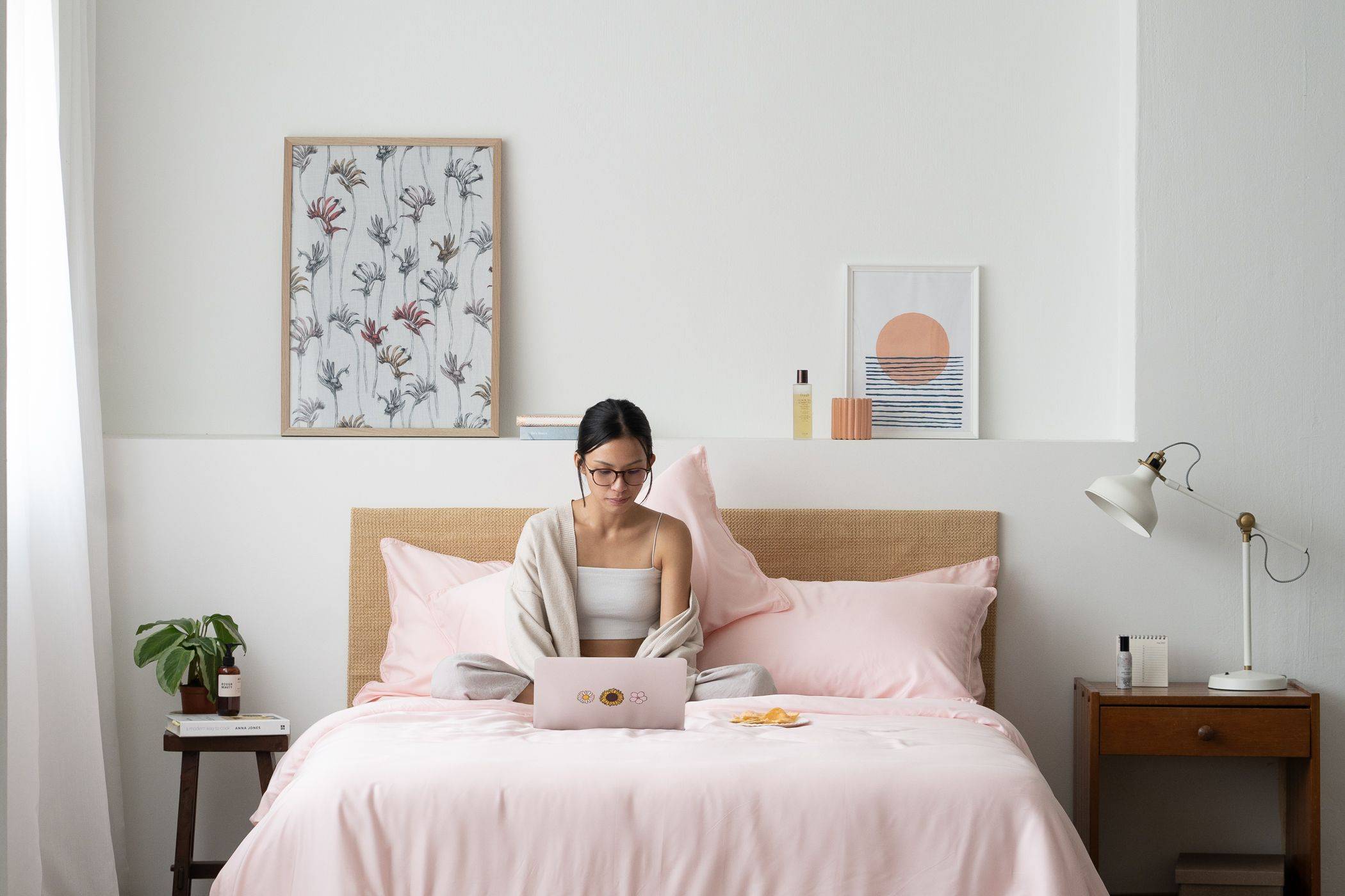 Girl on bed using her laptop, featuring Weavve's Lyocell Sheets in Blush Pink