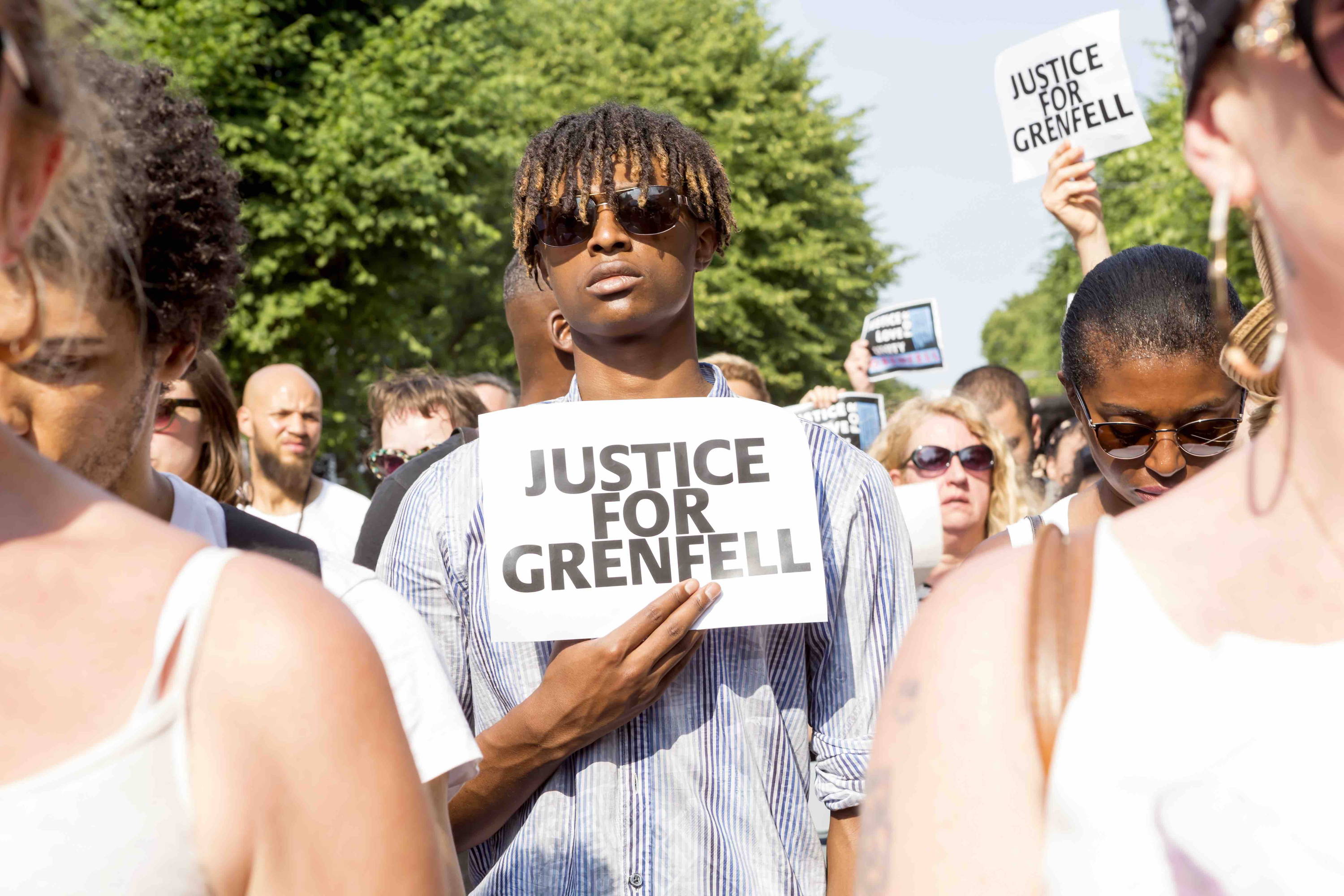 Young man in a crowd holding sign: Justice For Grenfell