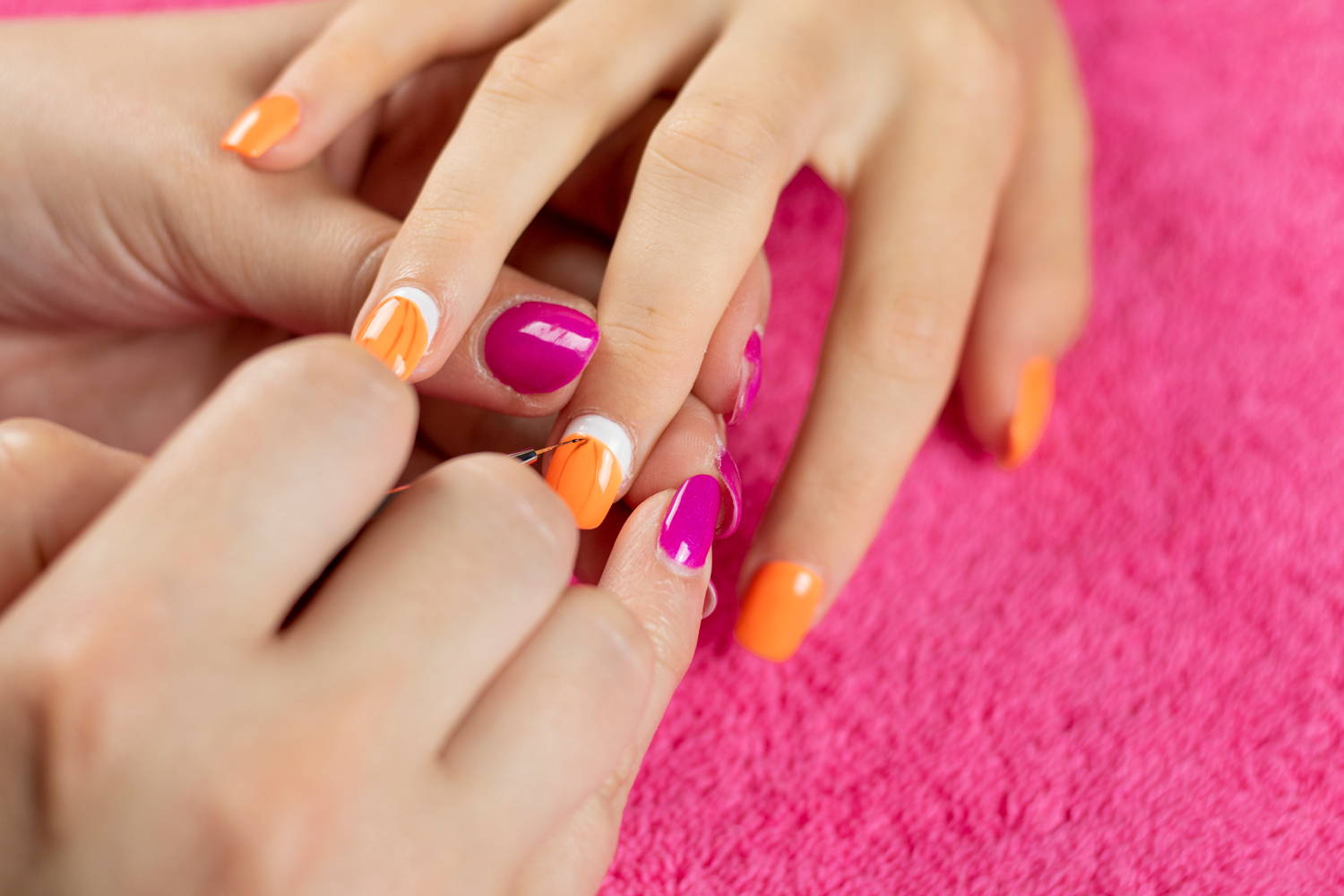 Pumpkin detailing being painted onto nails using ORLY Liquid Vinyl black nail polish