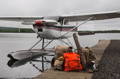 a pile of frost river packs sitting on a dock next to a byplane.