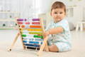 Cute baby boy playing with wooden abacus in his room. 