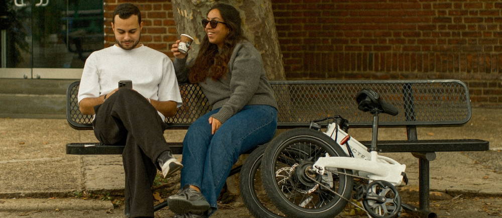 a man and woman on a bench near a folding bike