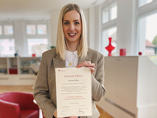 Zug
- Sabrina Huber mit ihrer Urkunde Immobilienvermarkter mit eidgenössischem Fachausweis in den Händen