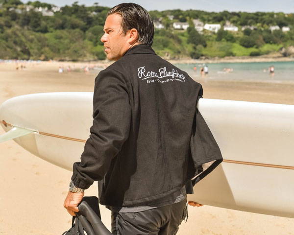 Man wearing black hemp jacket with logo embroidery from Cornish sustainable surf clothing brand Roma Surfshop