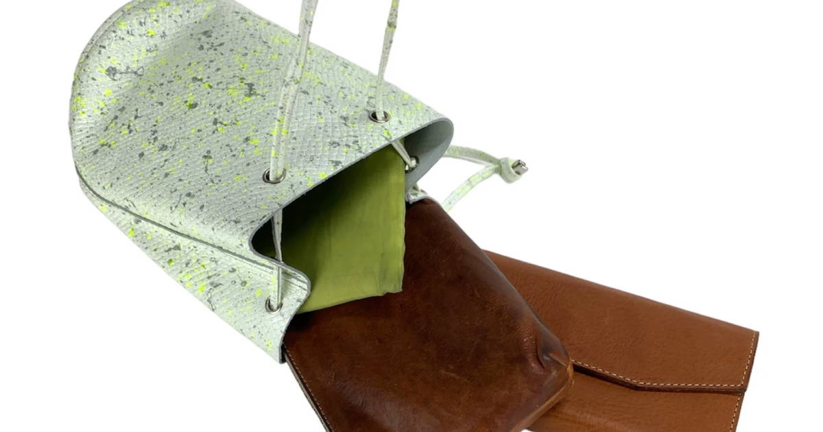 黄緑と深緑の模様がついたペールグリーンの巾着ショルダーバッグの中からノートなどが飛び出している。