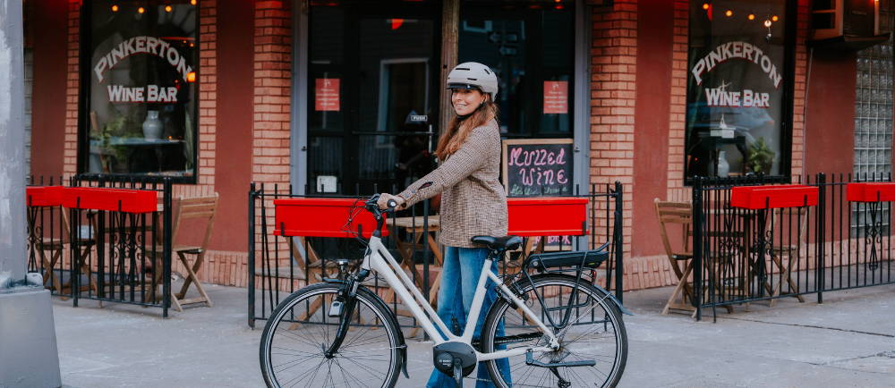 Woman walking with Gazelle electric bike on sidewalk 