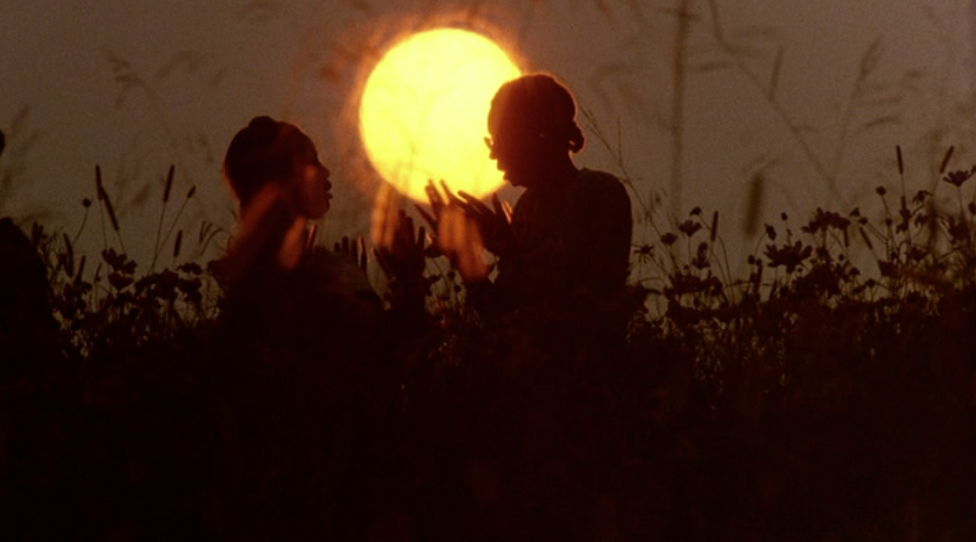Silhouette of Celie and Shug talking while the sun is setting in a field.