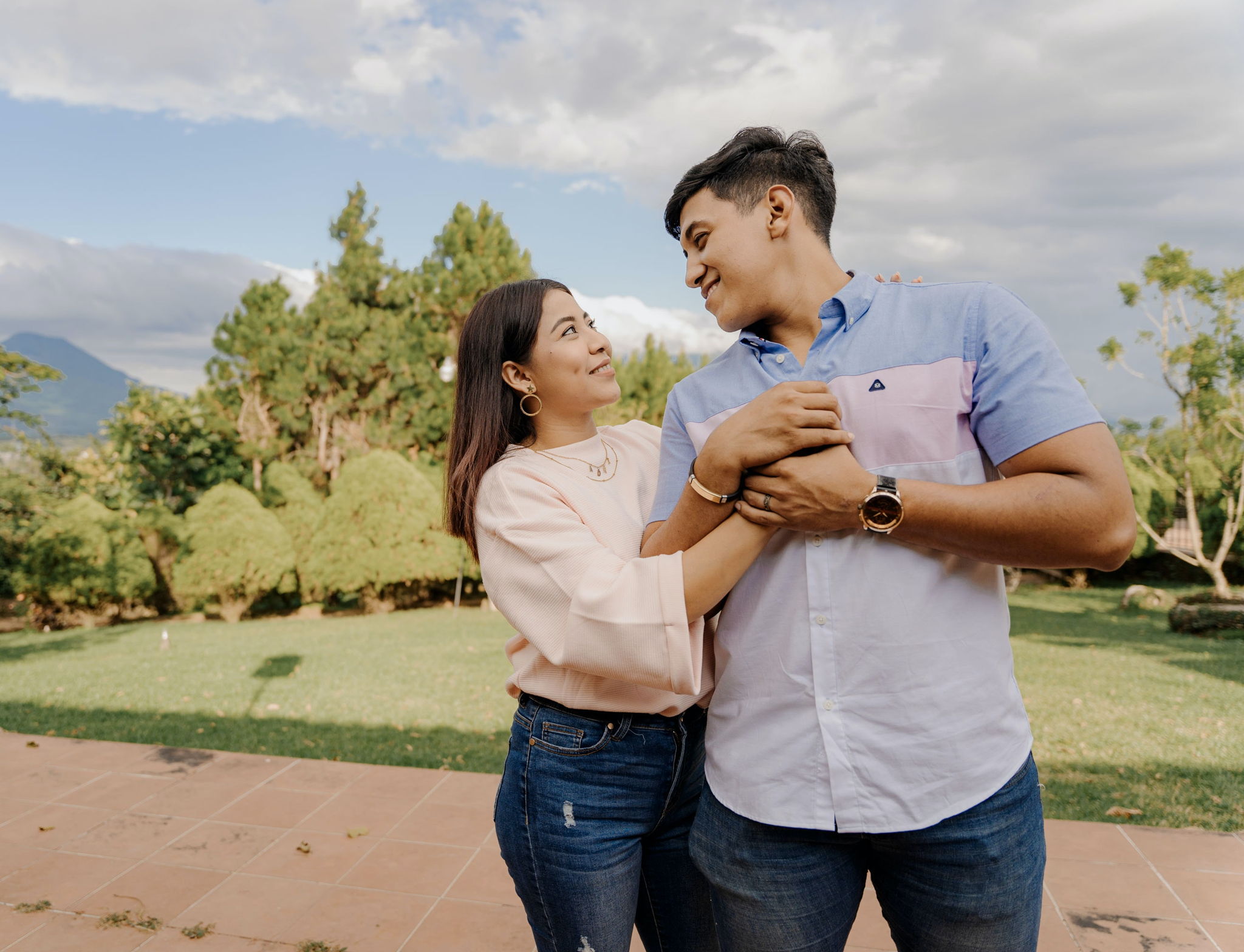 A young latin couple has an intimate moment holding onto eachother in the outdoors.