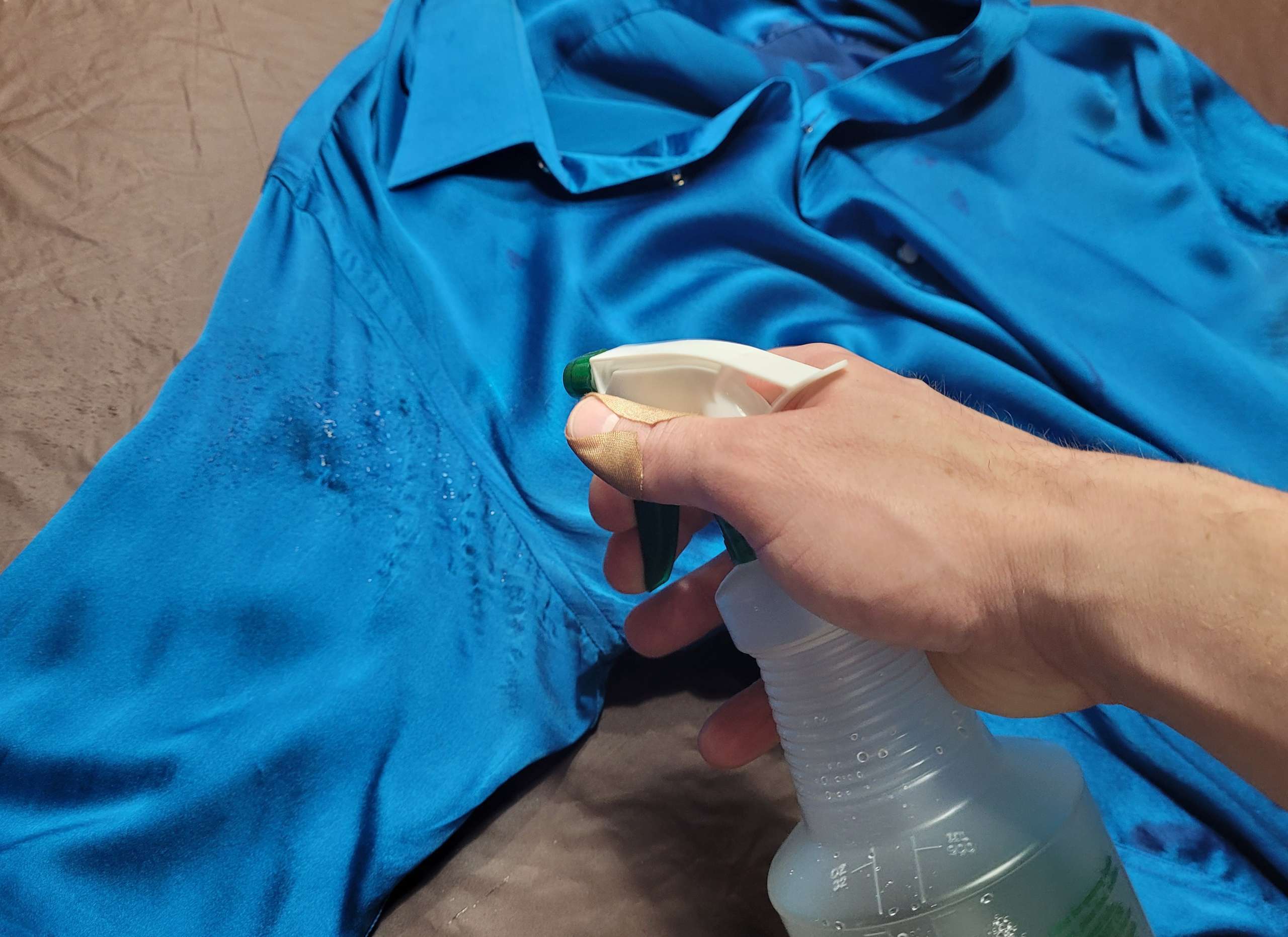 photo of a man spraying cleaning solution on sweat stains on a silk shirt