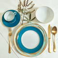 blue and white plates over a white hemstitched napkin with gold silverware on the sides