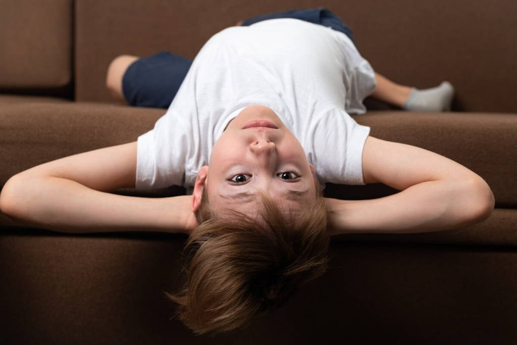 Boy laying upside down and looking at camera.