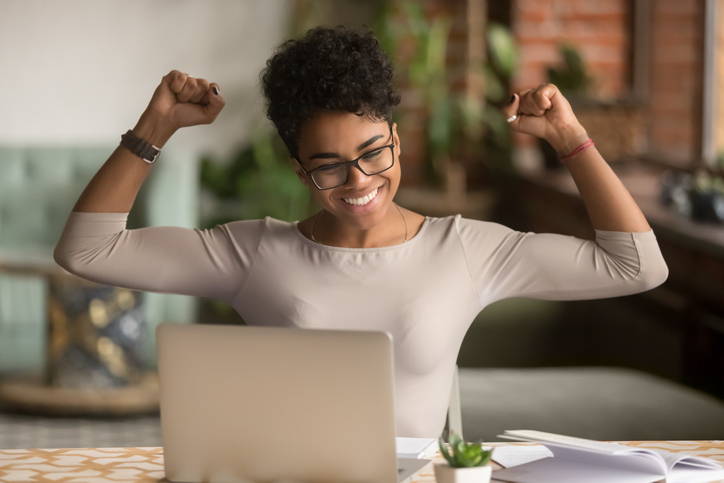 excited Black woman in front of a laptop