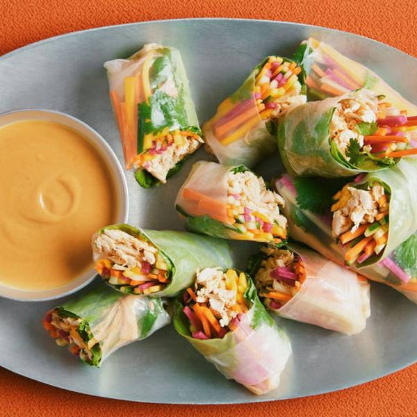 Shredded roast chicken, julienned mango, carrots, cucumbers, pickled radishes, cilantro leaves, and iceberg lettuce wrapped in rice paper and served on a platter with peanut sauce.