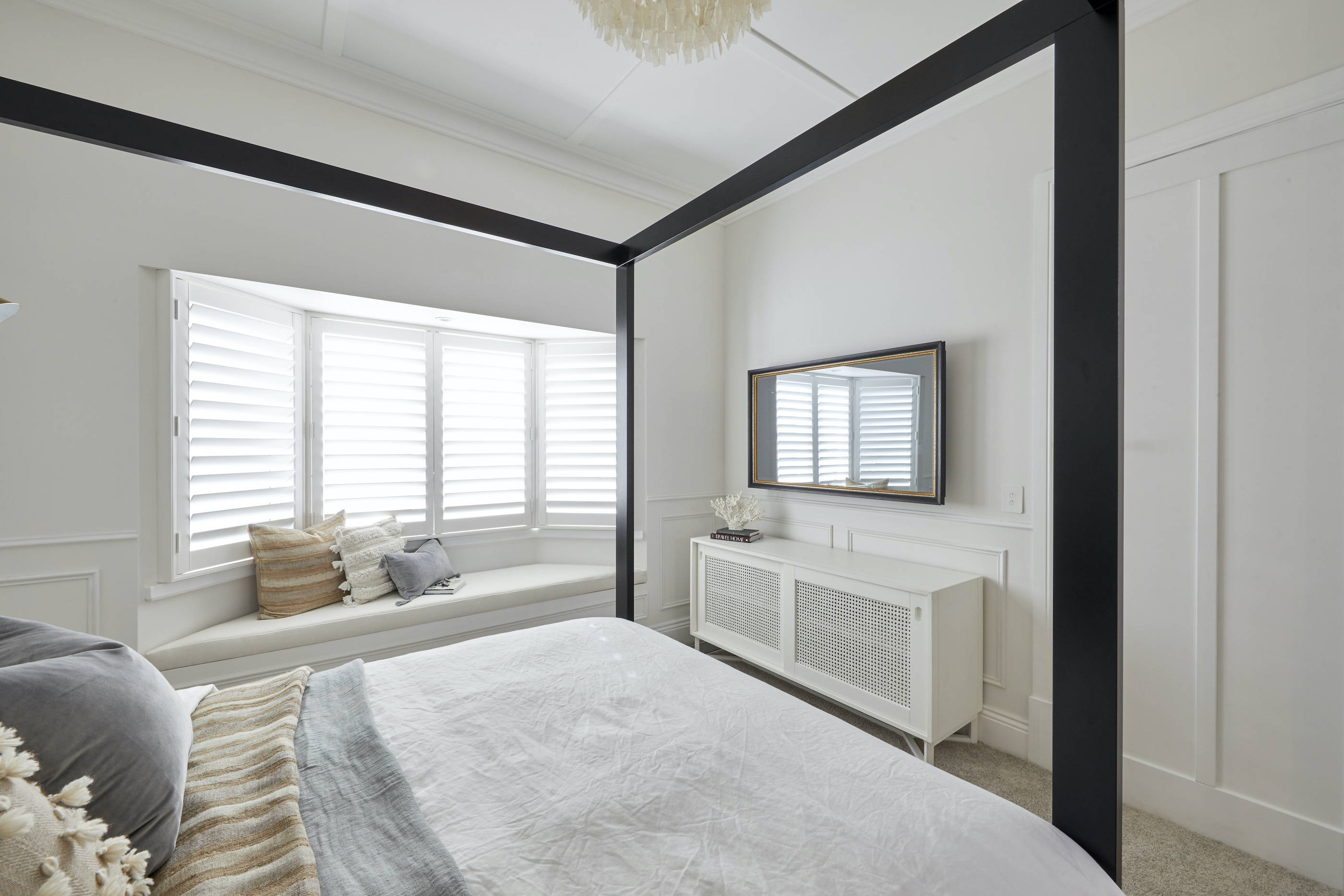 A TV-Mirror hanging on the wall of a coastal, elegant bedroom setting 