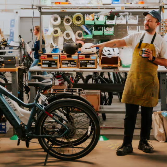 an upway mechanic pointing at 2 aventon electric bikes at an upway upcenter