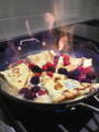 crepes flambeing in a pan with berries