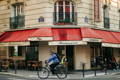 Homme à vélo passant devant une brasserie à Paris