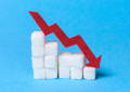 white sugar cubes set up like a staircase on a blue background; red arrow showing decline in blood sugar. Wheat grass may lower blood sugar levels.