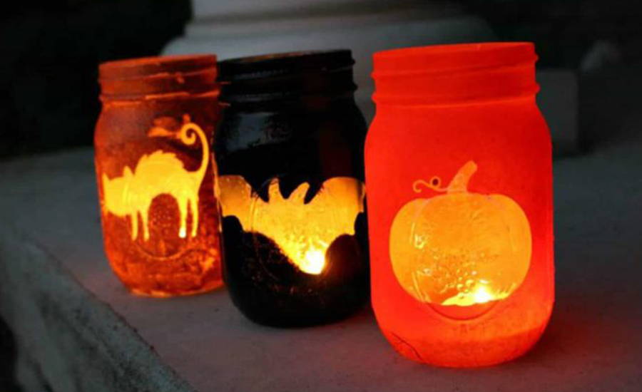 black and orange mason jars with halloween designs and candles