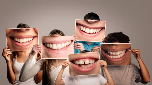 People holding up oversized photos of teeth