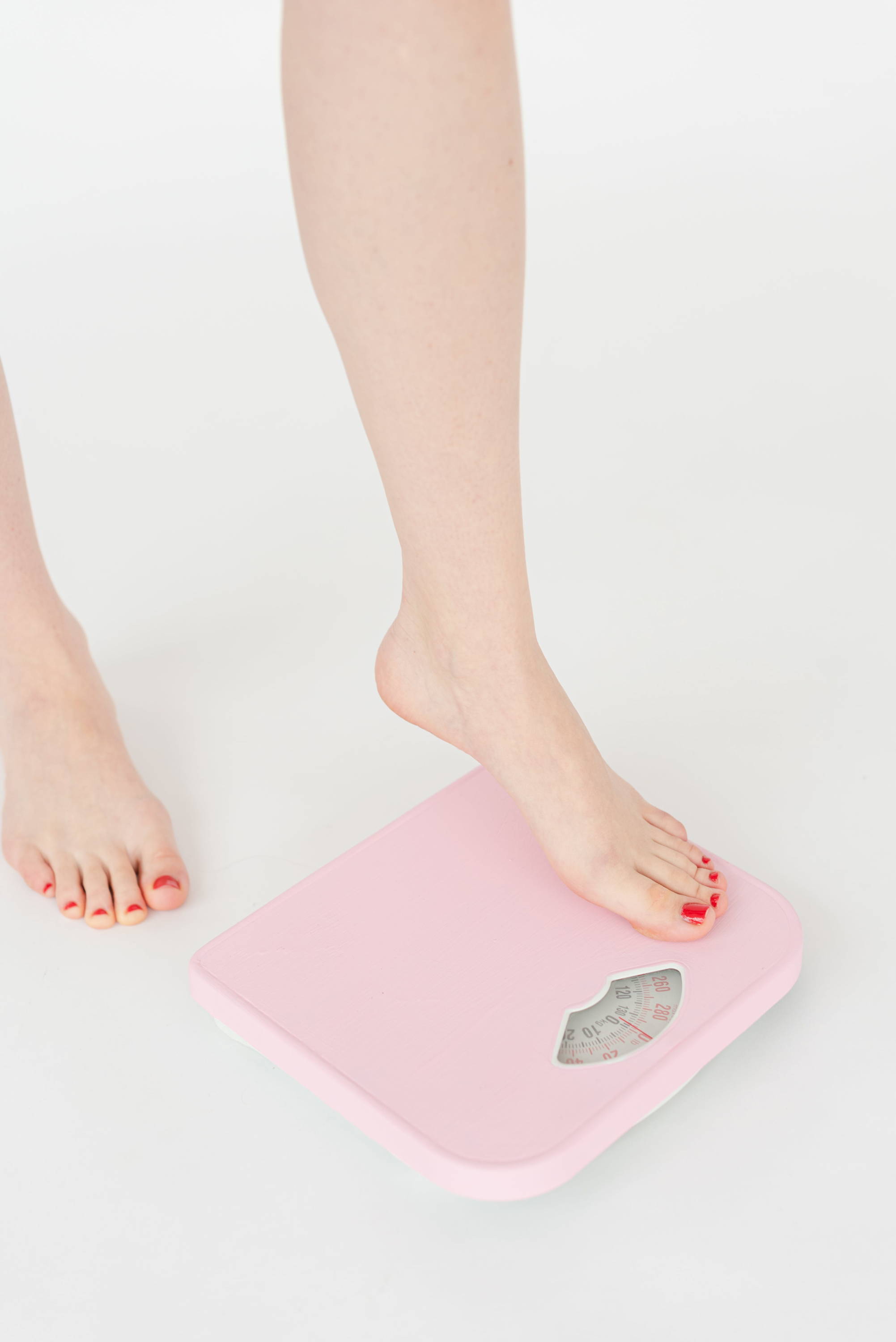 Woman's foot stepping on pink scale