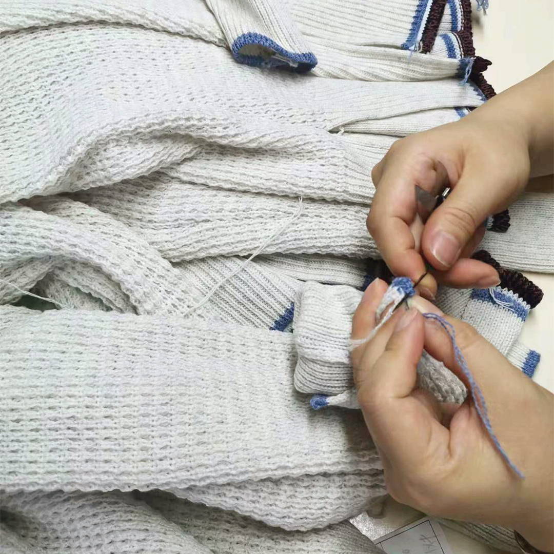 Hands working on the hem of a Margaret O'Leary sweater.