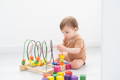 Cute baby playing with wooden Montessori multicolor blocks. 