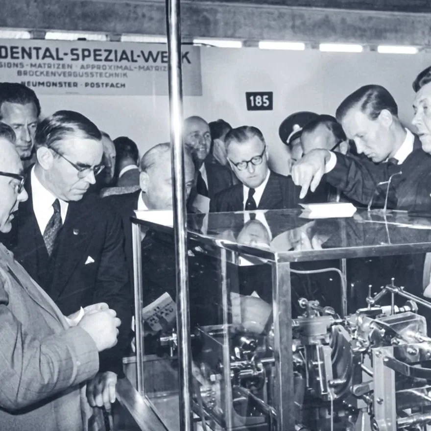 an image from the Komet archives showing industry professionals looking at the bur manufacturing machine in the 1950s