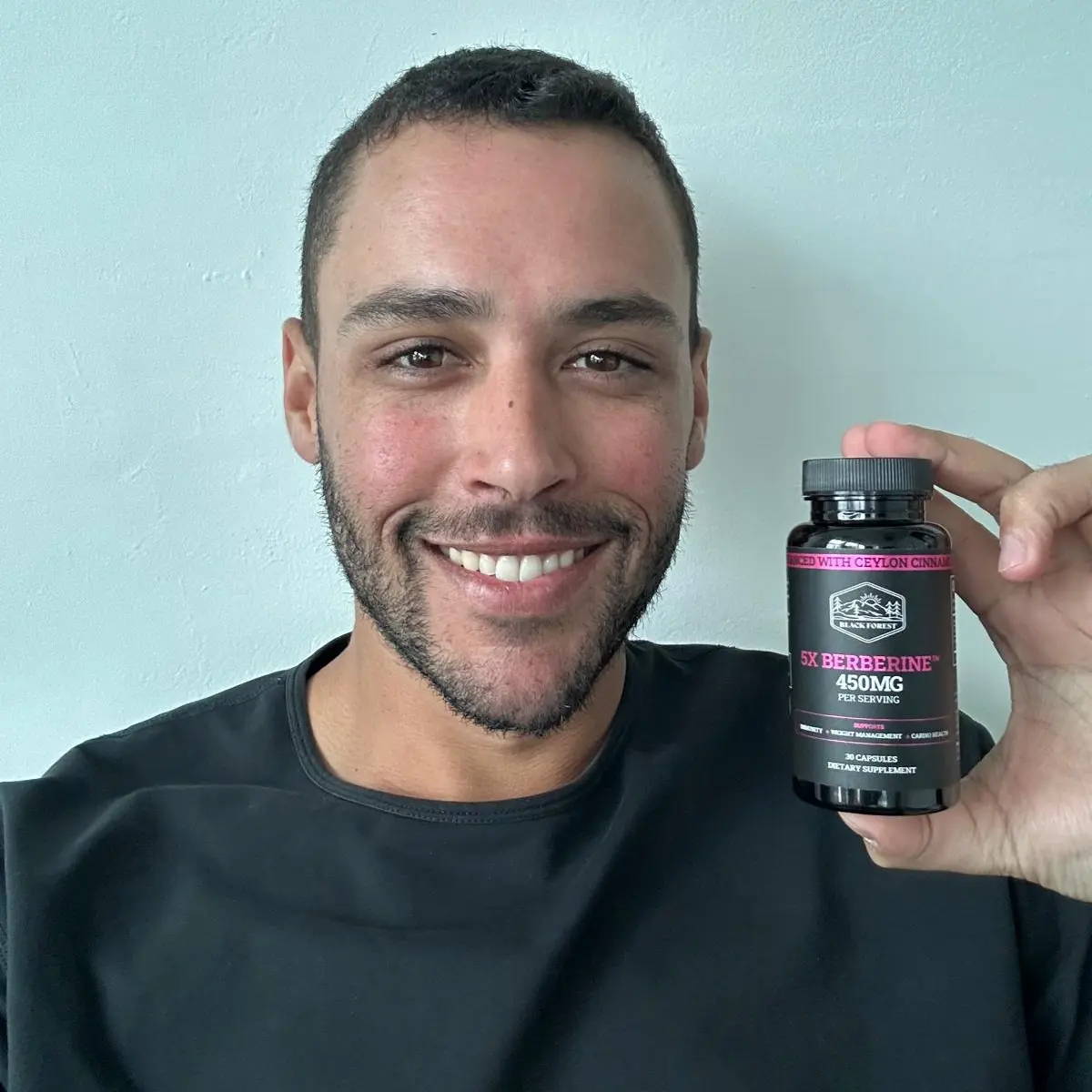 A smiling man holding a berberine bottle