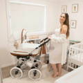 A woman posing in her nursery with her white YORK pram