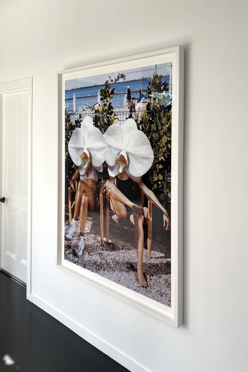 'Ladies in Waiting' by Dina Broadhurst - A photographic print of two girls with crossed legs in garden chairs, with white orchids over the top of the image creating a collage-effect.