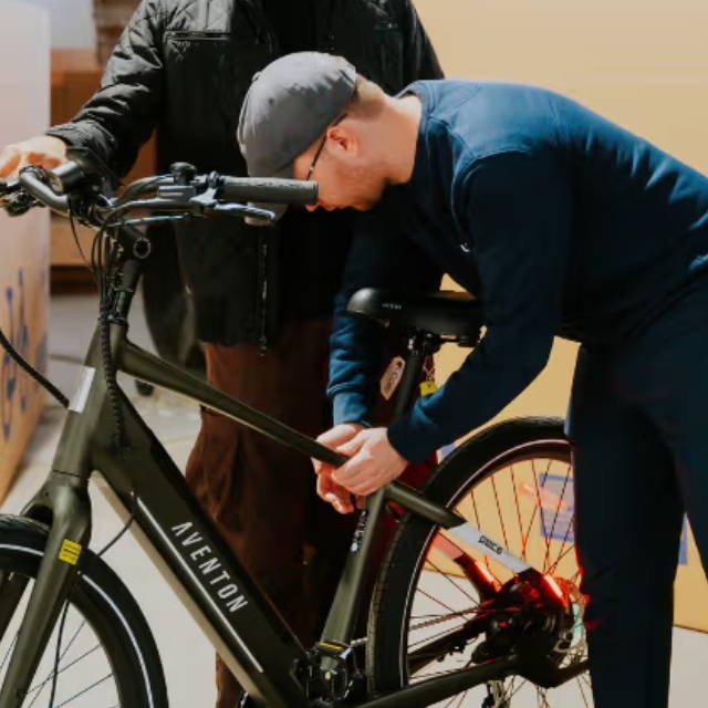 two people standing over an aventon electric city bike at an upway upcenter