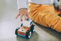 Toddler playing with a wooden car toy. 