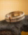 Exquisite gold and pearl bracelet with square-cut stones displayed on a dark wooden surface against a warm golden backdrop