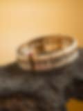 Exquisite gold and pearl bracelet with square-cut stones displayed on a dark wooden surface against a warm golden backdrop
