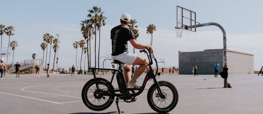 Rider on Rad Power RadRunner electric bike near basketball court