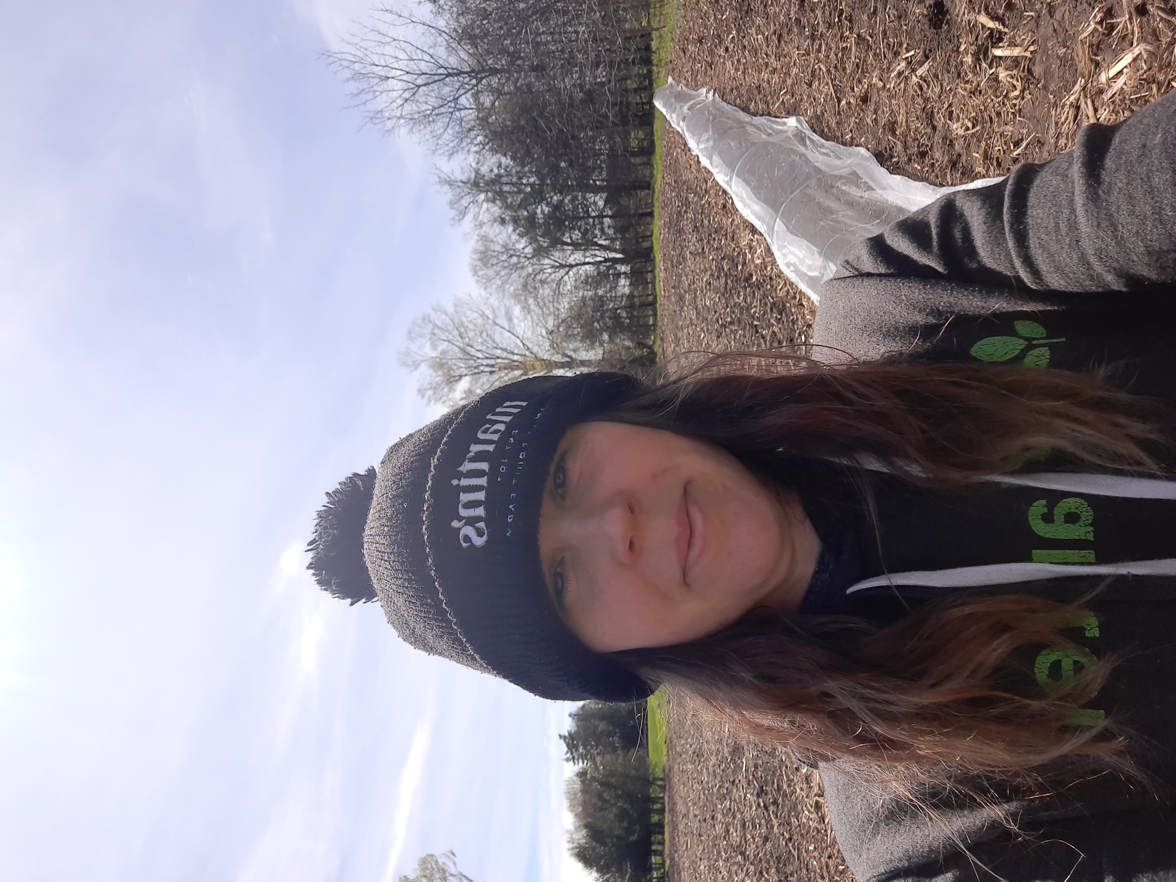 The author, Erin, in the field with a garden bed in the background covered in insect netting.