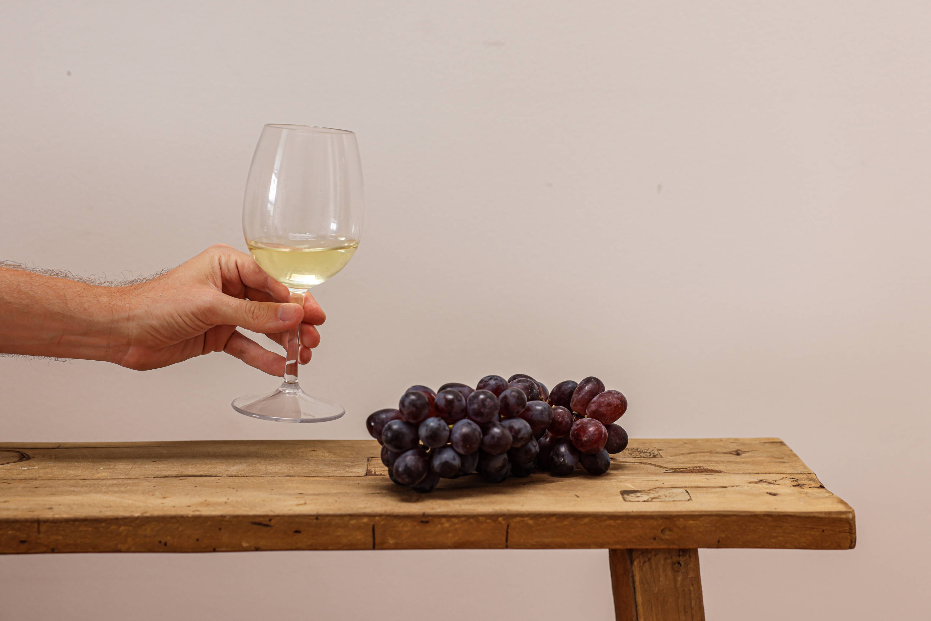Wooden bench with grapes and a glass of white wine. 