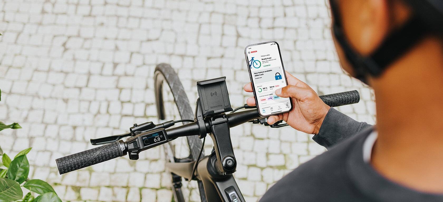 Cycliste consultant l'application de son vélo électrique connecté sur un smartphone fixé au guidon
