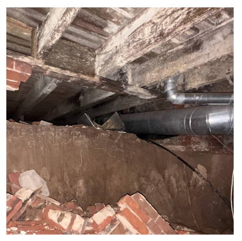 Exposed foundation with damaged bricks under a house, indicating structural issues.