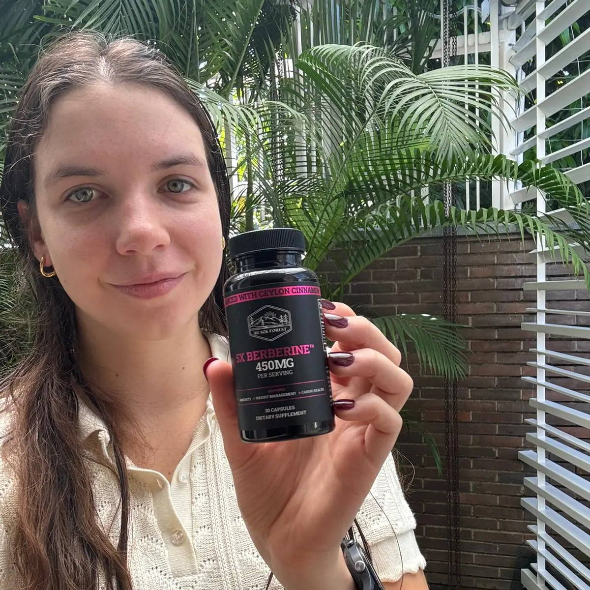 A smiling woman holding a berberine bottle