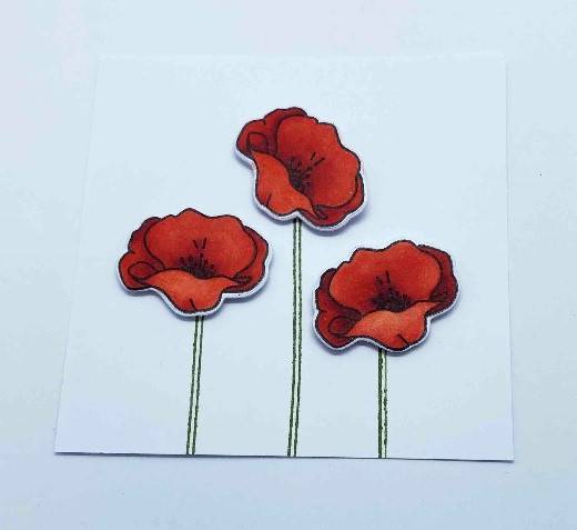 Poppies that are coloured in using a red alcohol marker are stuck down on the Safari Green stamped stems using foam pads