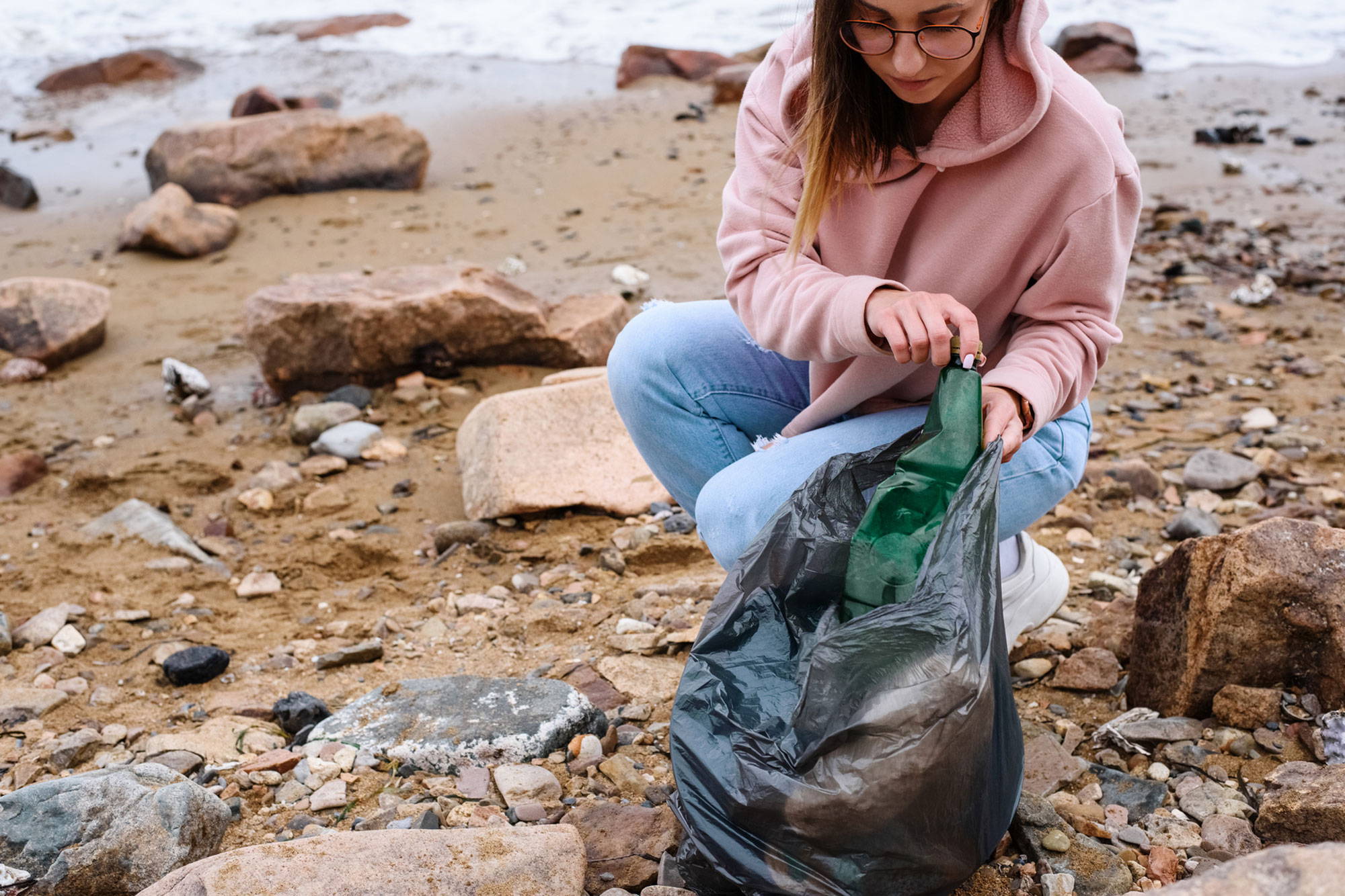 woman picking up trash by the beach