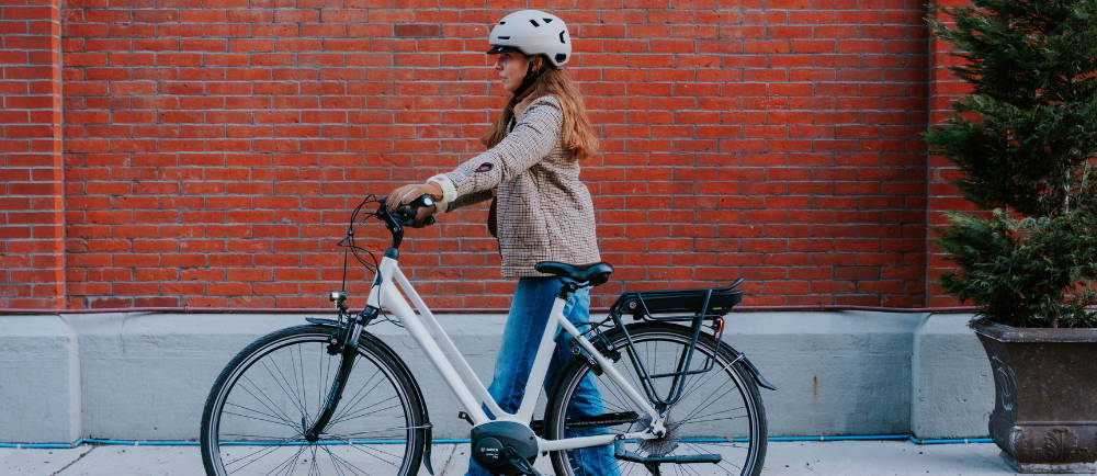 a woman walking a Gazelle Medeo electric city bike
