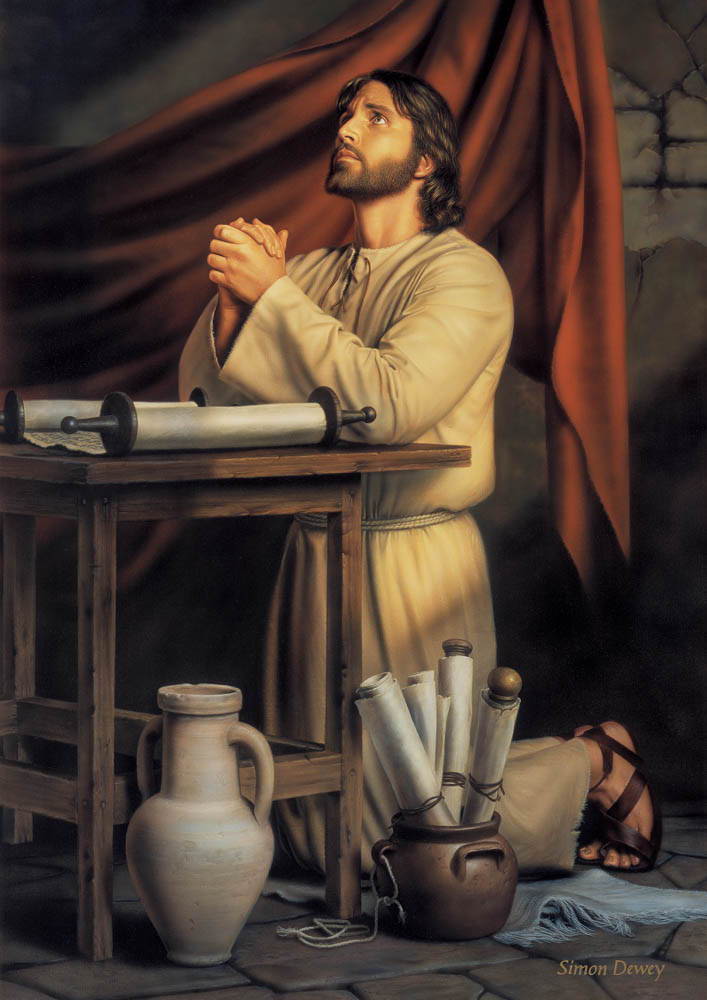 Jesus kneeling in prayer at a desk. A scroll is spread out on the desk while more sit at the foot.