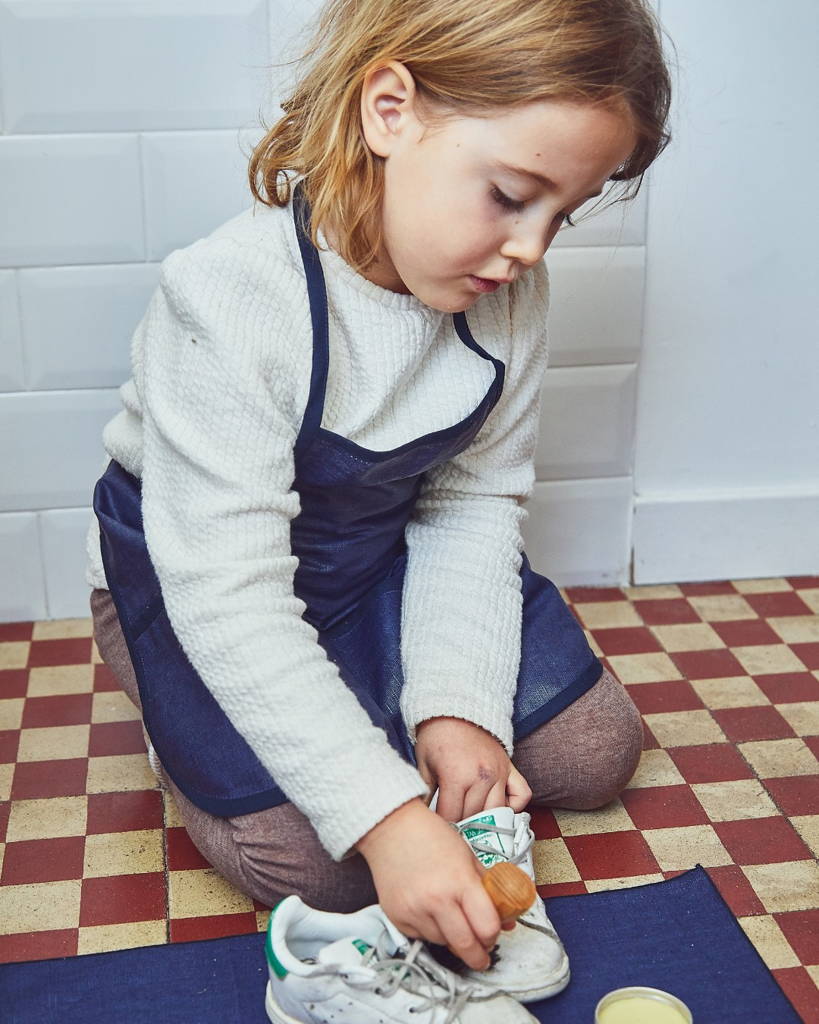 Une petite fille réalise une activité Montessori pour cirer ses chaussures