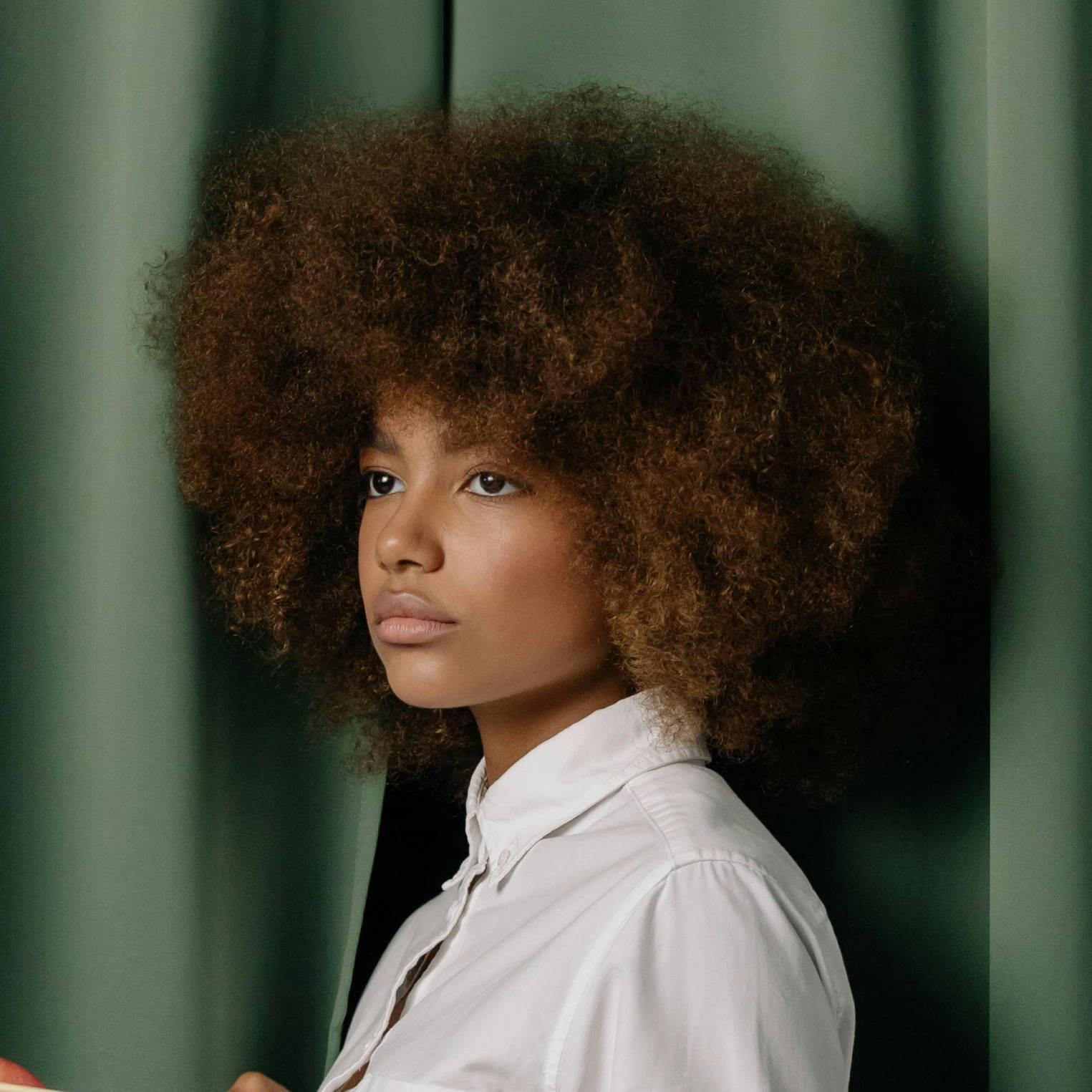 woman with brown afro in front of green curtains