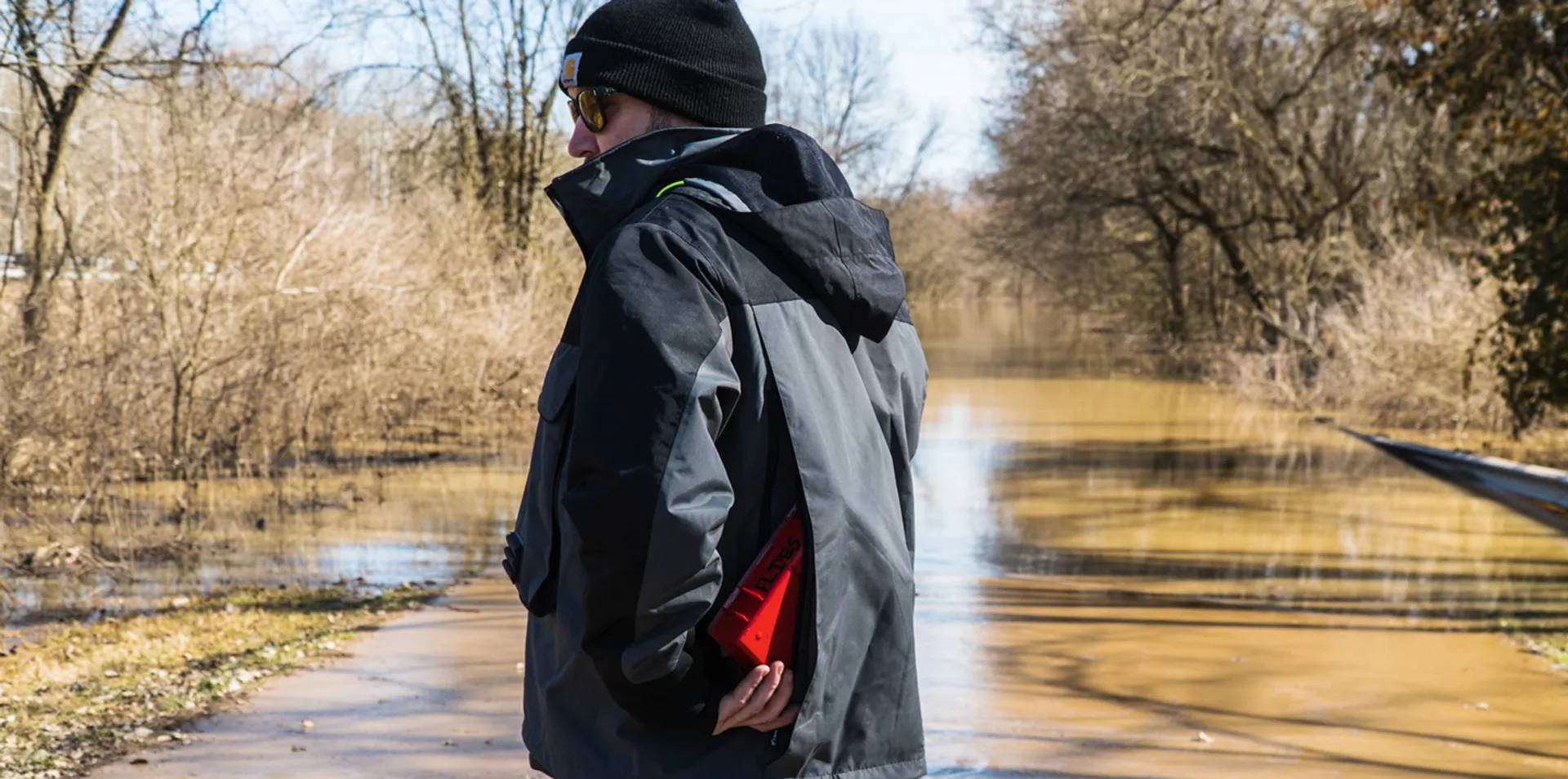The man is showing the large capacity pocket into the back of the fishing jacket